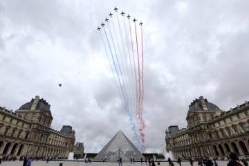 TOPSHOTSNine alphajets from the French Air Force Patrouille de France release trails of blue, white and red smoke, colors of French national flag, as they fly over Louvre museum and the Louvre Pyramid during the Bastille Day military parade in Paris, on July 14, 2012.  AFP PHOTO /KENZO TRIBOUILLARDKENZO TRIBOUILLARD/AFP/GettyImages
